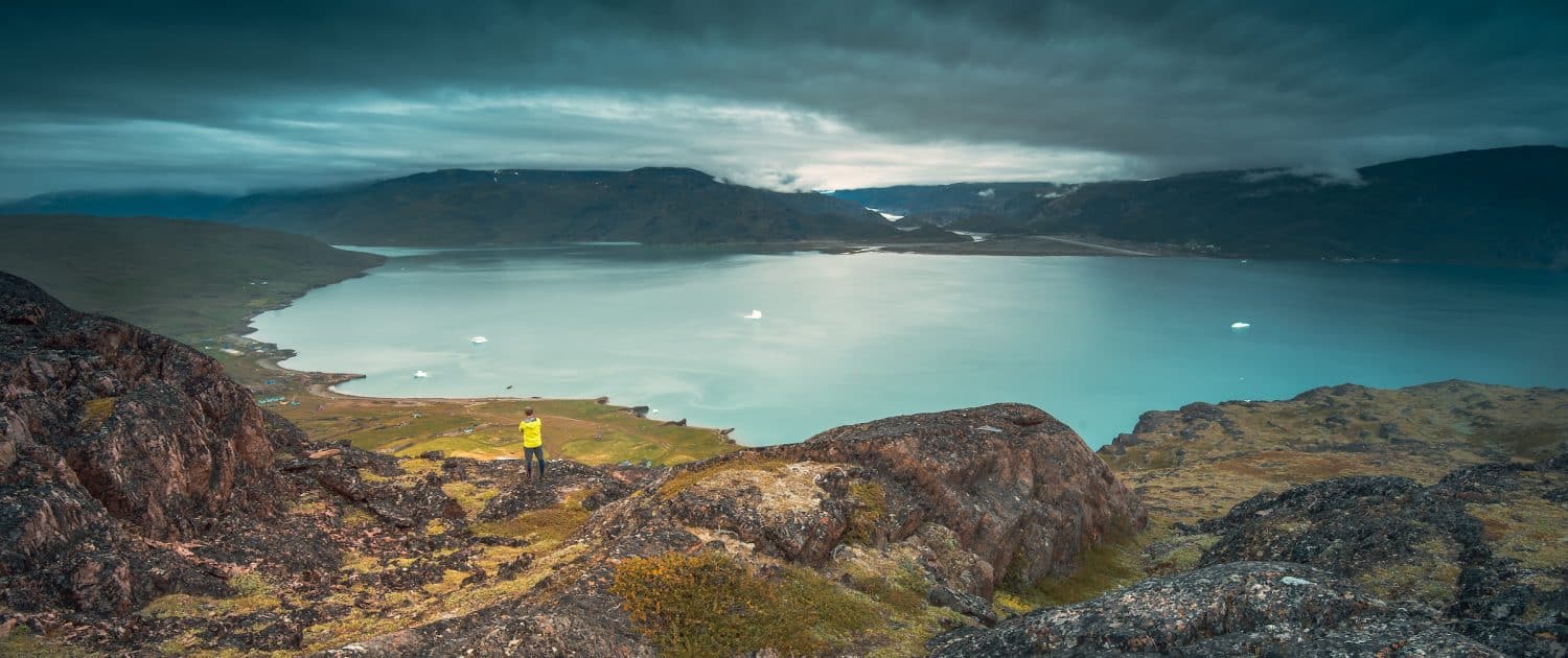 A lone traveller stands in Qassiarsuk and looks over Tunulliarfik Fjord toward Narsarsuaq. Photo by Stacy William Head