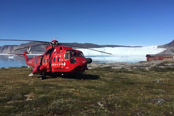 Red helicopter about to take off close to the water. Photo by Arctic Nomad