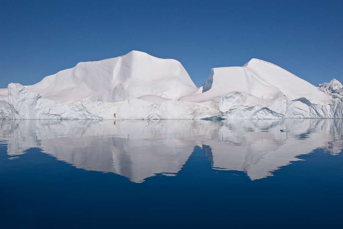 Large iceberg under clear blue skies. Photo by Thomas Eltorp, Visit Greenland
