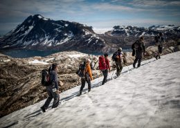 Greenland Travel hikers passing through lingering snow on the mountain near Tiniteqilaaq in East Greenland. By Mads Pihl