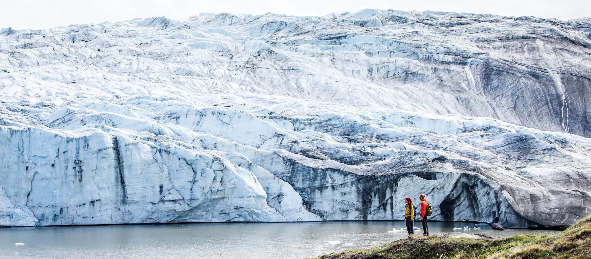 Two hikers reach the Russell Glacier, part of the Greenland Ice Sheet, in the Kangerlussuaq backcountry. By Raven Eye Photography