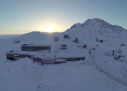 Aerial view of the hotel with sunrise in background in Winter. Photo by Hotel Angmagssalik - Visit Greenland