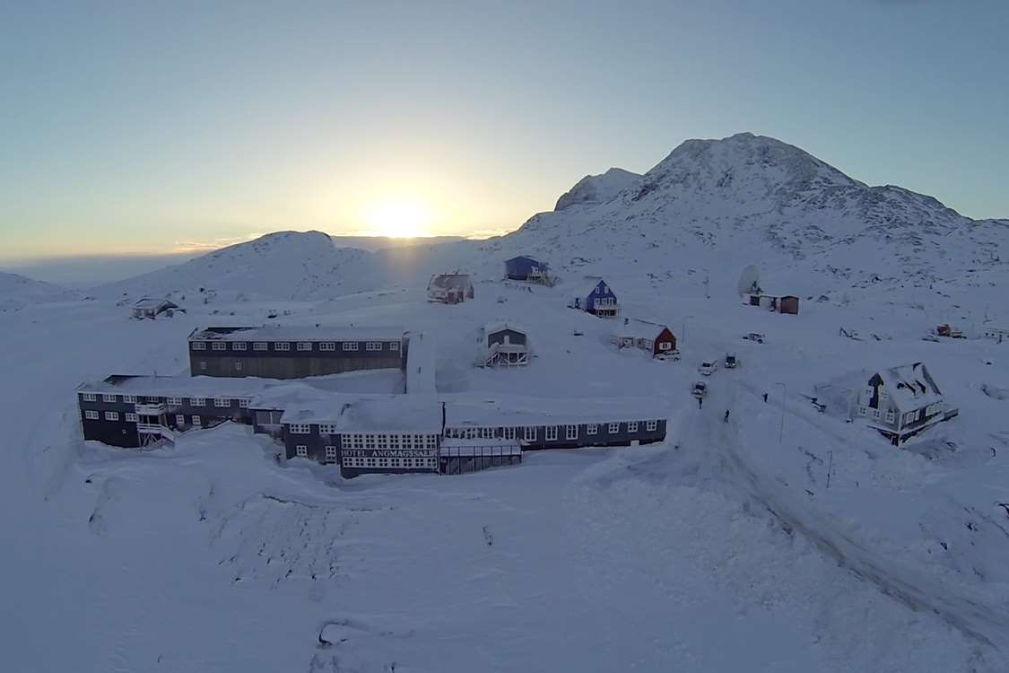 Aerial view of the hotel with sunrise in background in Winter. Photo by Hotel Angmagssalik - Visit Greenland