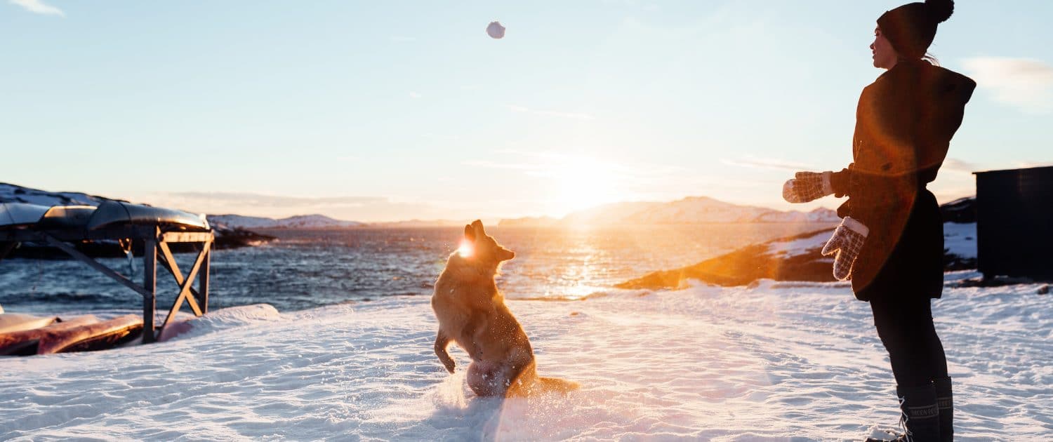 Local make up artist Natascha playing with her dog in the snow during sunset in Nuuk in Greenland. Photo by Rebecca Gustafsson