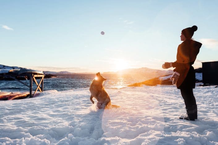 Local make up artist Natascha playing with her dog in the snow during sunset in Nuuk in Greenland. Photo by Rebecca Gustafsson
