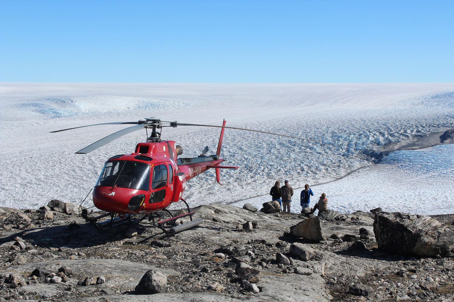 Tourists standing next to a helicopter while looking at the Greenland Ice Sheet. Photo by Arctic Nomad