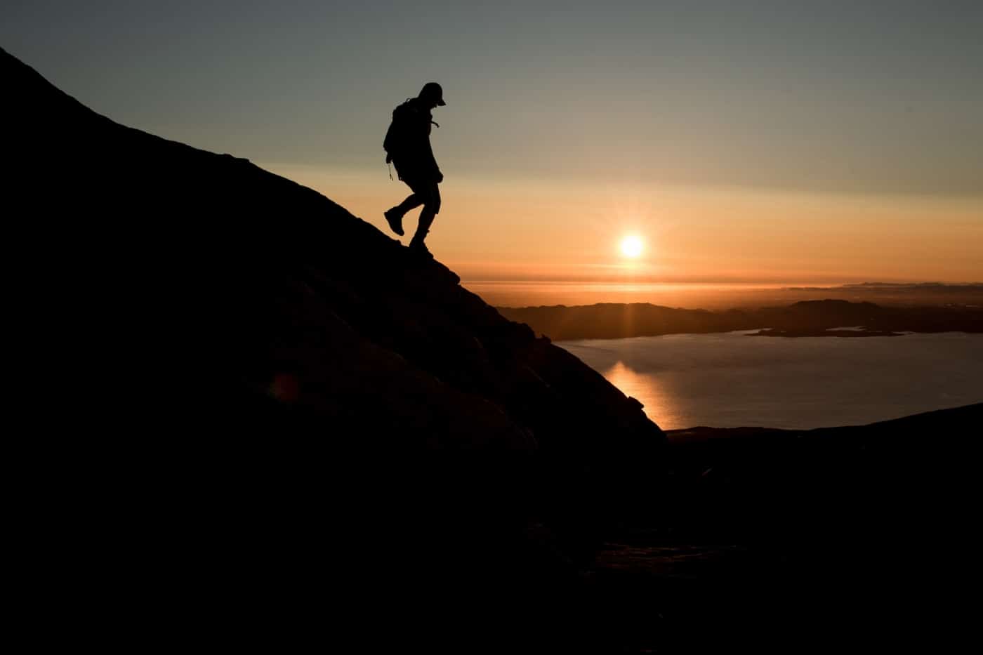 A hiker descending the mountain Ukkusissaq - Store Malene in the midnight sun outside Nuuk in Greenland. By Mads Pihl