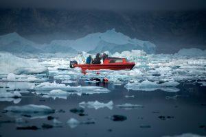People on a boat taking photos of icebergs and mountains. Photo by Arctic Dream, Visit Greenland
