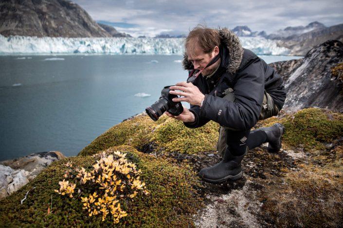 A photographer shooting flowers and plants by the Knud Rasmussen Glacier in East Greenland. By Mads Pihl