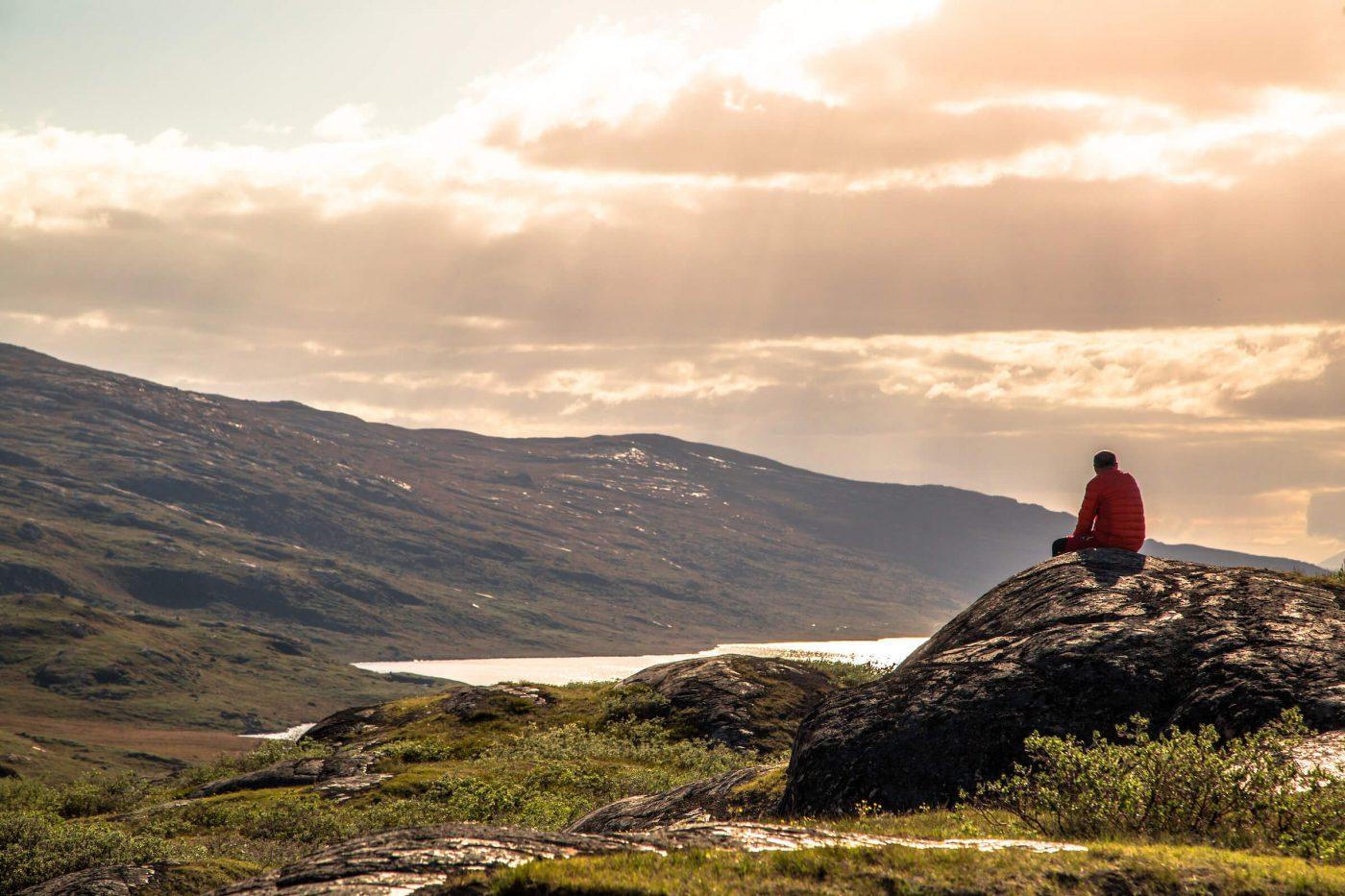 Hiker enjoys a relaxing and reflective moment in the Arctic Circle backcountry. By Raven Eye Photography