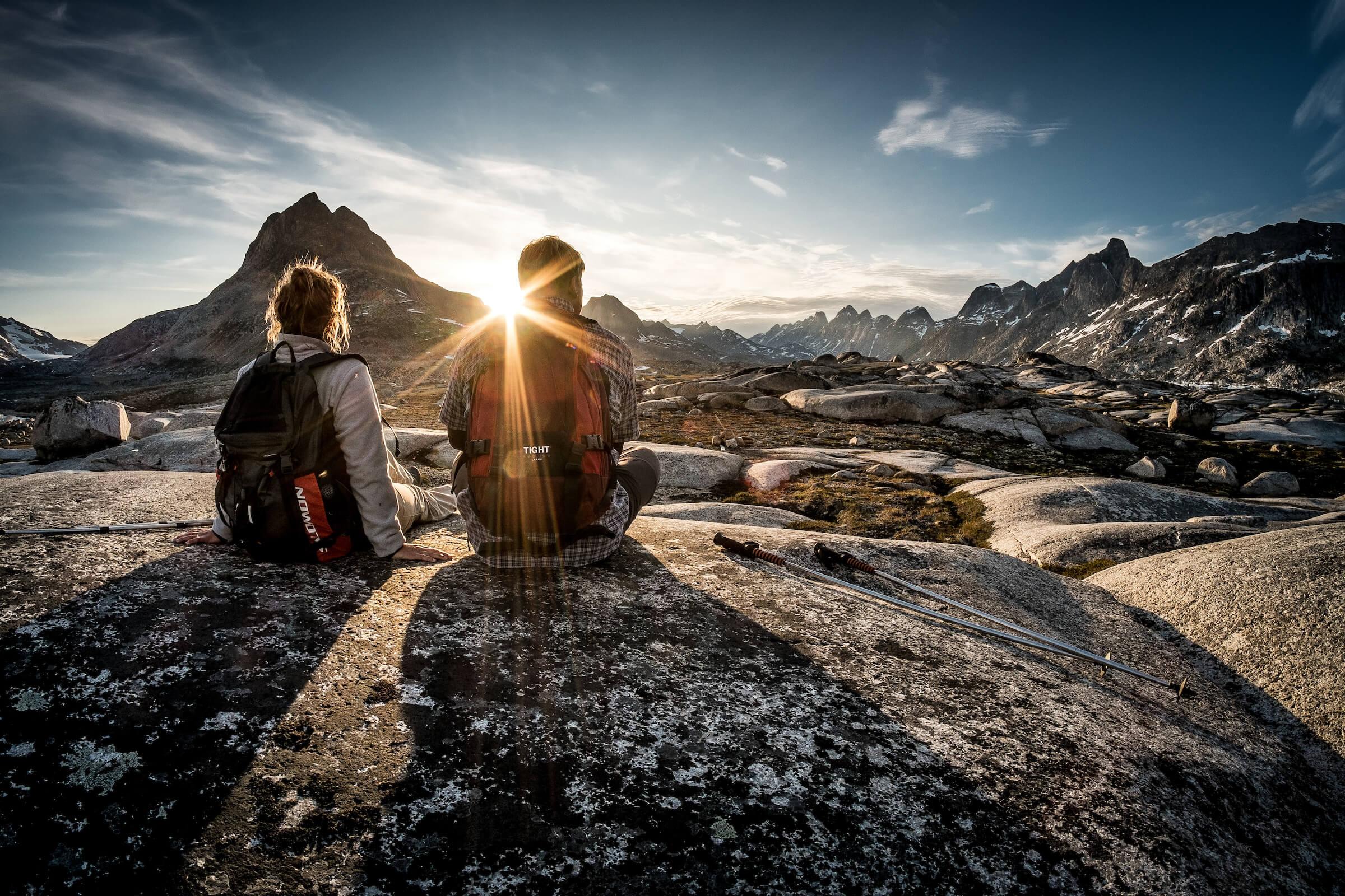 Midnight Sun - Two hikers enjoying the sunset near Qenertivartivit in Ammassalik Fjord near Kulusuk in East Greenland