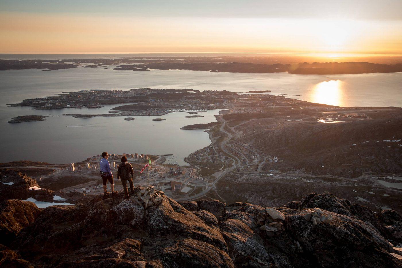 Two hikers overlooking Nuuk in the midnight sun from the peak of Ukkusissaq - Store Malene in Greenland. By Mads Pihl