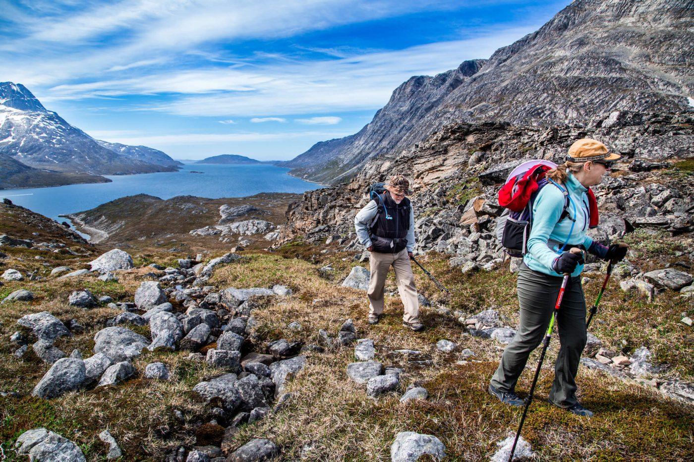 Two mature travelers hiking in the Nuuk backcountry with Touring Greenland crossing from the bottom of Kobbefjord over to Nuuk Fjord. Photo by Raven Eye Photography