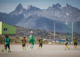 A game of soccer in Nanortalik in South Greenland with a backdrop of rugged peaks. Photo by Mads Pihl.