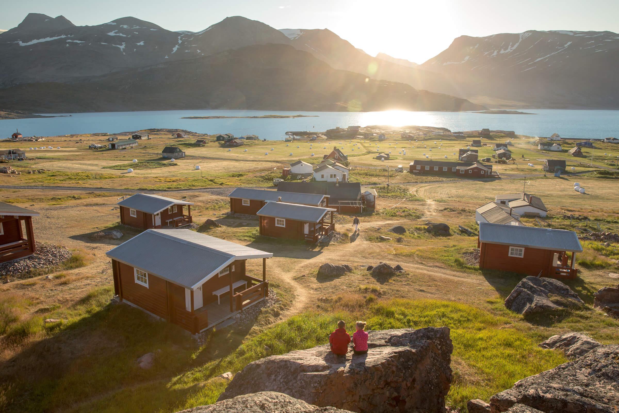 Two guests enjoying the sunset at the Blue Ice hut accommodation in Igaliku in South Greenland. Photo by Mads Pihl.