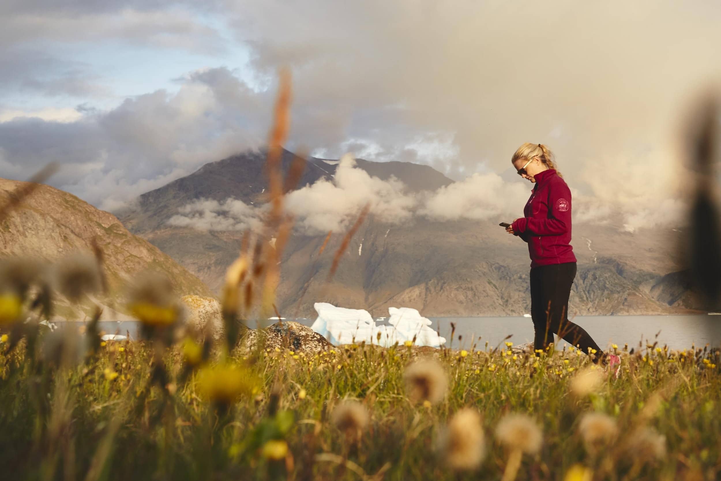 Female tourist looking at phone in Inneruulalik South Greenland by Photo by Peter Lindstrøm, Visit Greenland