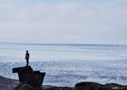 Person standing on a rock looking over the large greenlandic icecap. Photo by Wild Greenland, Visit Greenland