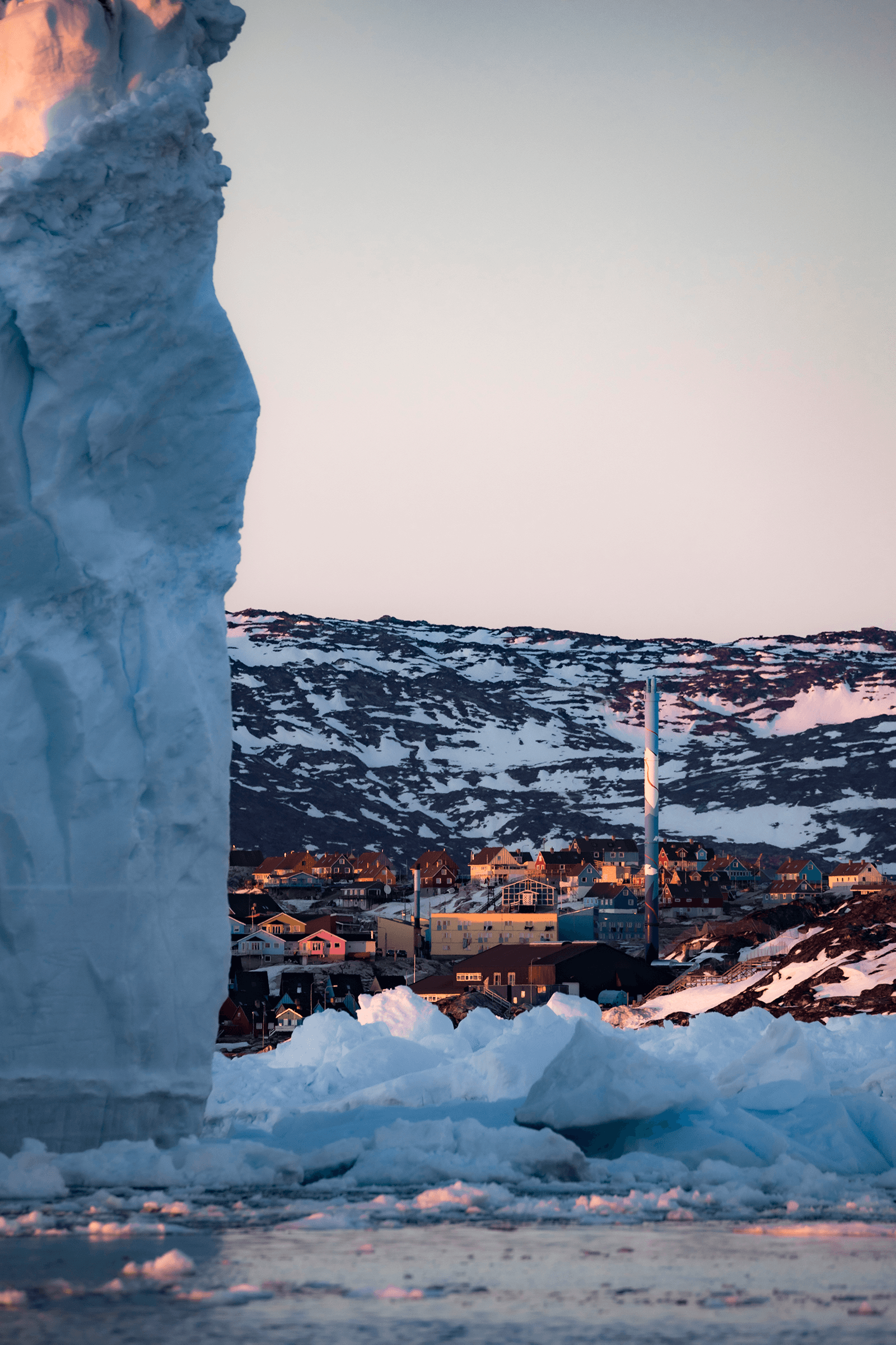 Nukissiorfiit in Ilulissat with huge iceberg. Photo by Aningaaq R Carlsen - Visit Greenland