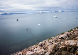 A hunter trying to catch a little auk with a net on stone hill near Siorapaluk. Photo by Insuk - Visit Greenland