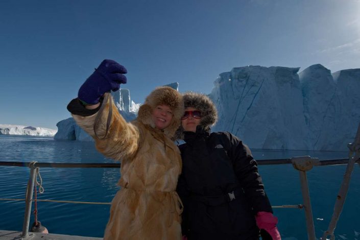 Two people taking a selfie infront of an iceberg. Photo by Thomas Eltorp