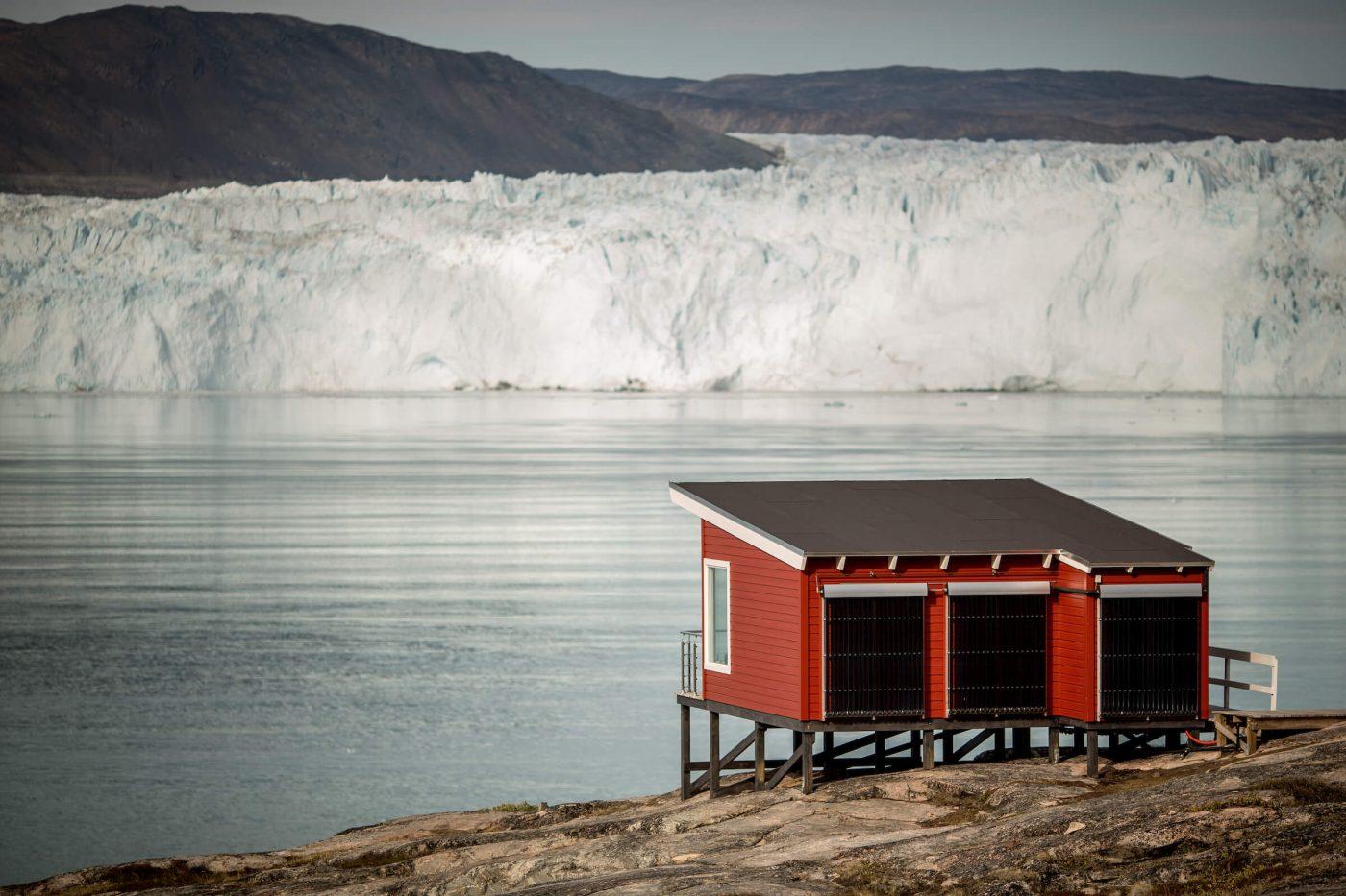 A comfort hut at Eqi Glacier Lodge with the glacier in the background in North Greenland. Photo by Mads Pihl