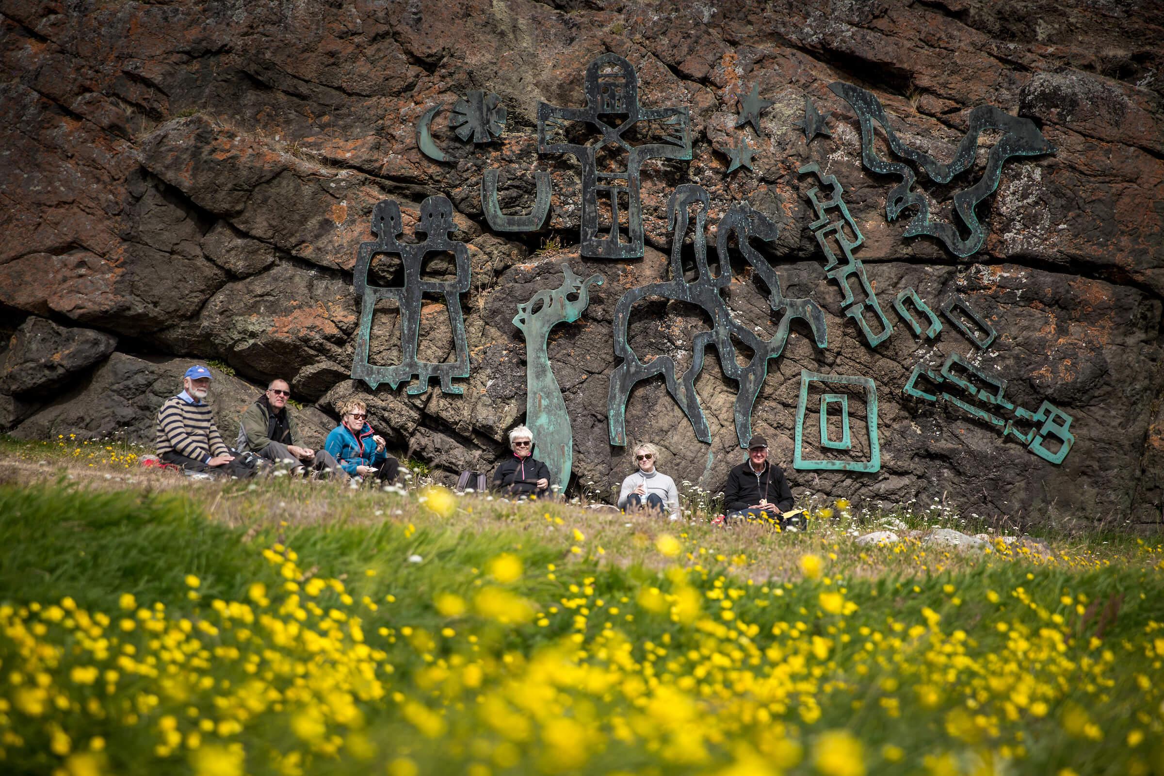 A group of travelers having lunch in front of the Sven Havsteen Mikkelsen artwork in Qassiarsuk. By Mads Pihl - Visit Greenland