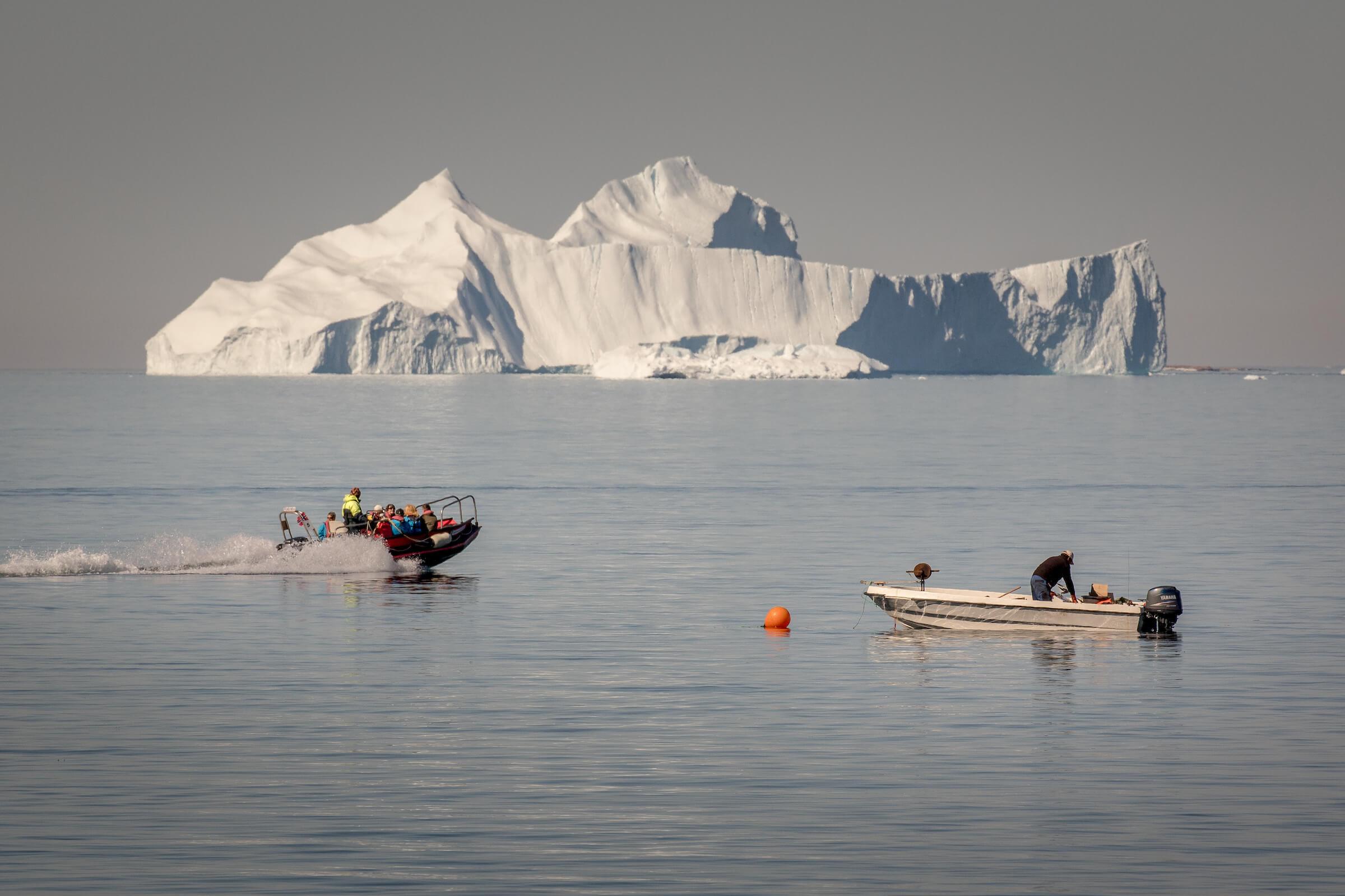 A tenderboat from MS Fram going past a fisherman at work in Upernavik in Greenland. By Mads Pihl