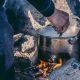 Guide cooking backcountry dinner over an open fire near the Arctic Circle. By Raven Eye Photography