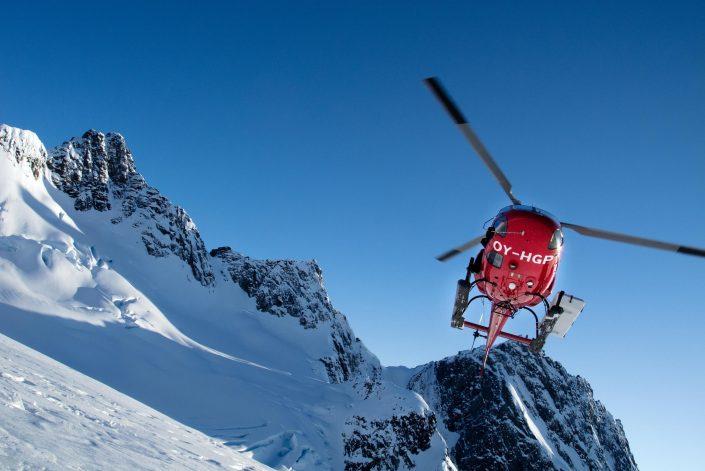 Air Greenland helicopter flying above mountains. By Humbert Entress
