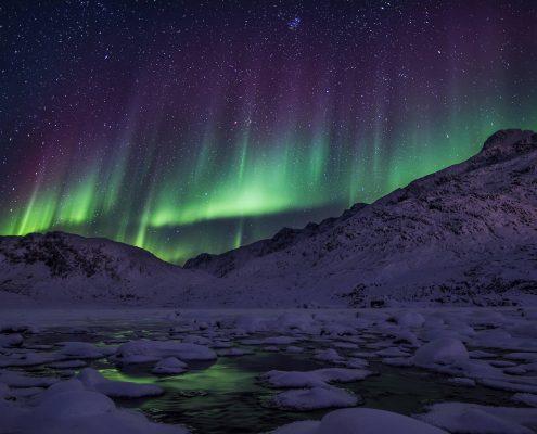 Northern lights over mountains. By Mads Pihl