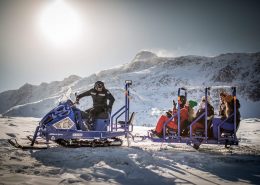Passengers on the Sisimiut snowmobile bus in Greenland having fun in the sun. Photo by Mads Pihl