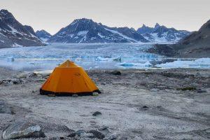 Orange tent camping by Knud Rasmussen glacier in East Greenland. Photo by Pirhuk - Greenland Expedition Specialists