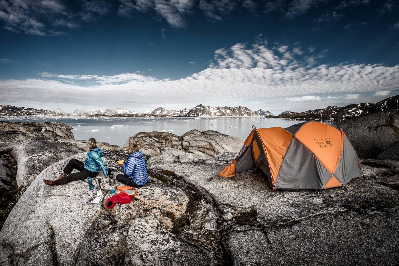 Two hikers enjoying the view from Qernertivartivit over Ammassalik Fjord in East Greenland. By Mads Pihl