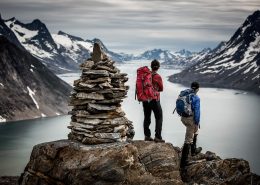 Two hikers on a Greenland Travel trek looking out over Ikaasatsivaq sound in East Greenland near Tiniteqilaaq. By Mads Pihl
