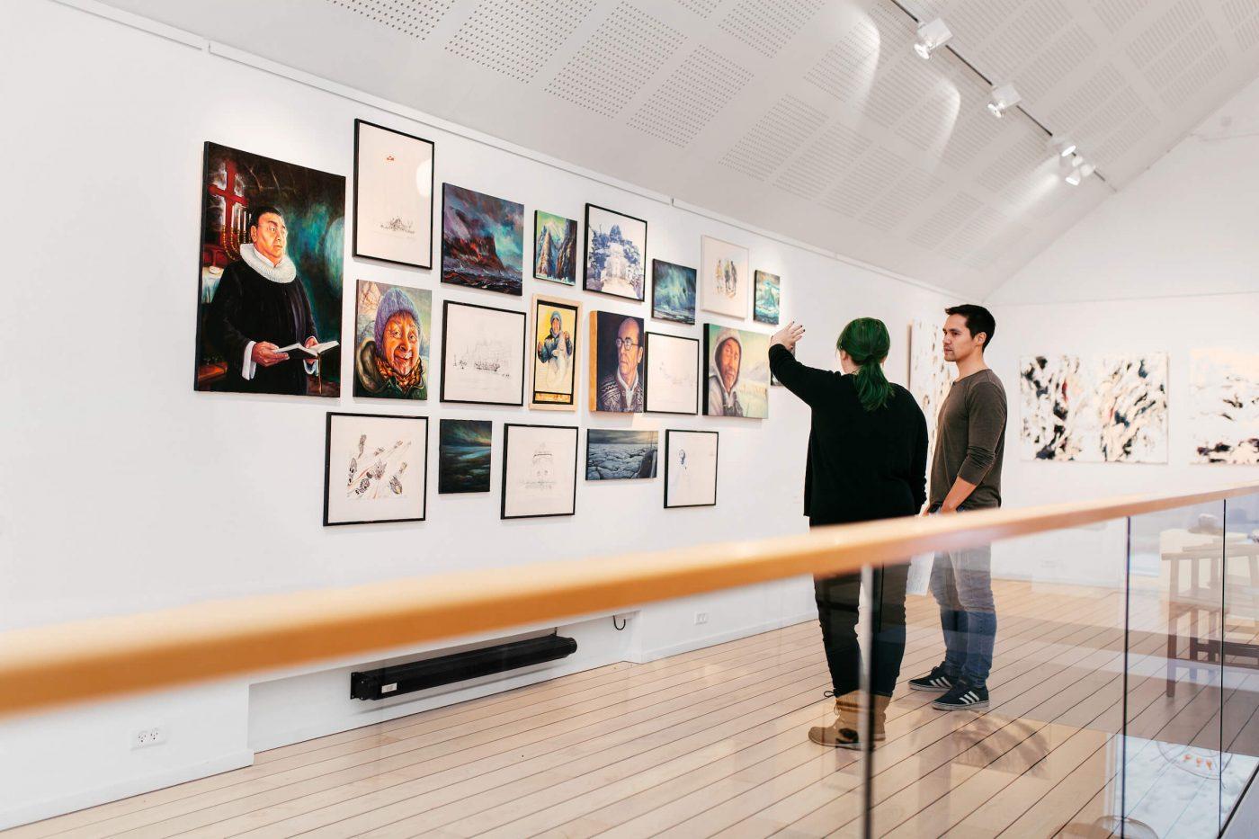 Visitors of Nuuk Art Museum talking about and looking at art from the Kimik exhibition. Photo by Rebecca Gustafsson